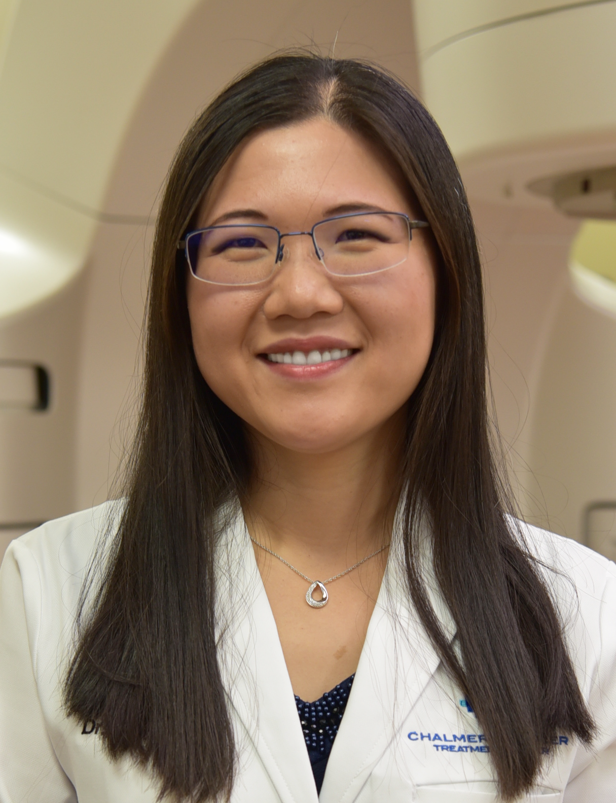 Dr. Shirley Butler-Xu, Radiation Oncologist, Hutchinson Regional Healthcare System, looking and smiling at camera with TrueBeam™ Linear Accelerator blurred out in background