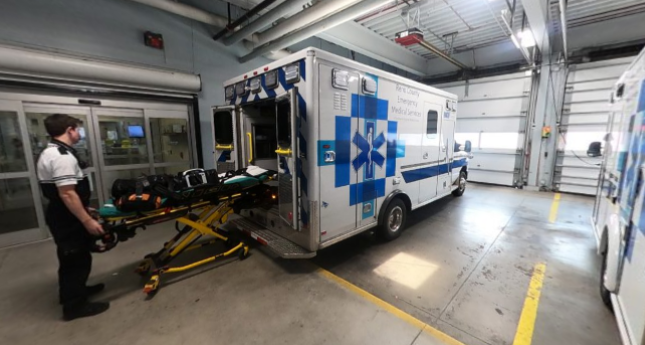 EMT loading a gurney into an ambulance in the EMS bay.