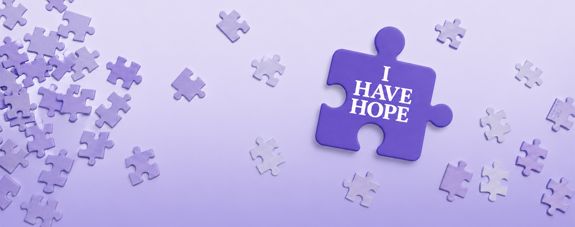Purple puzzle piece with the words I Have Hope surrounded by floating puzzle pieces on a soft lavender background.